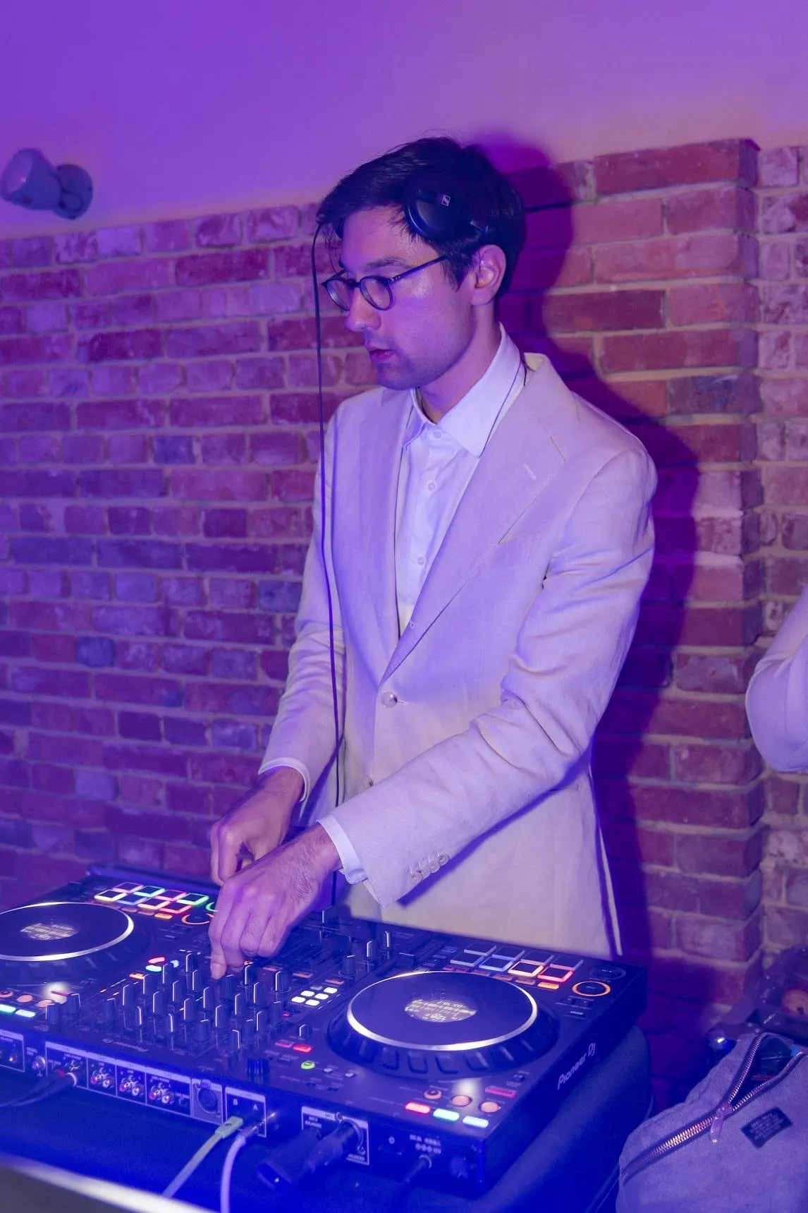 Un DJ Georges Walt aux platines, sous les lumières violettes de la soirée