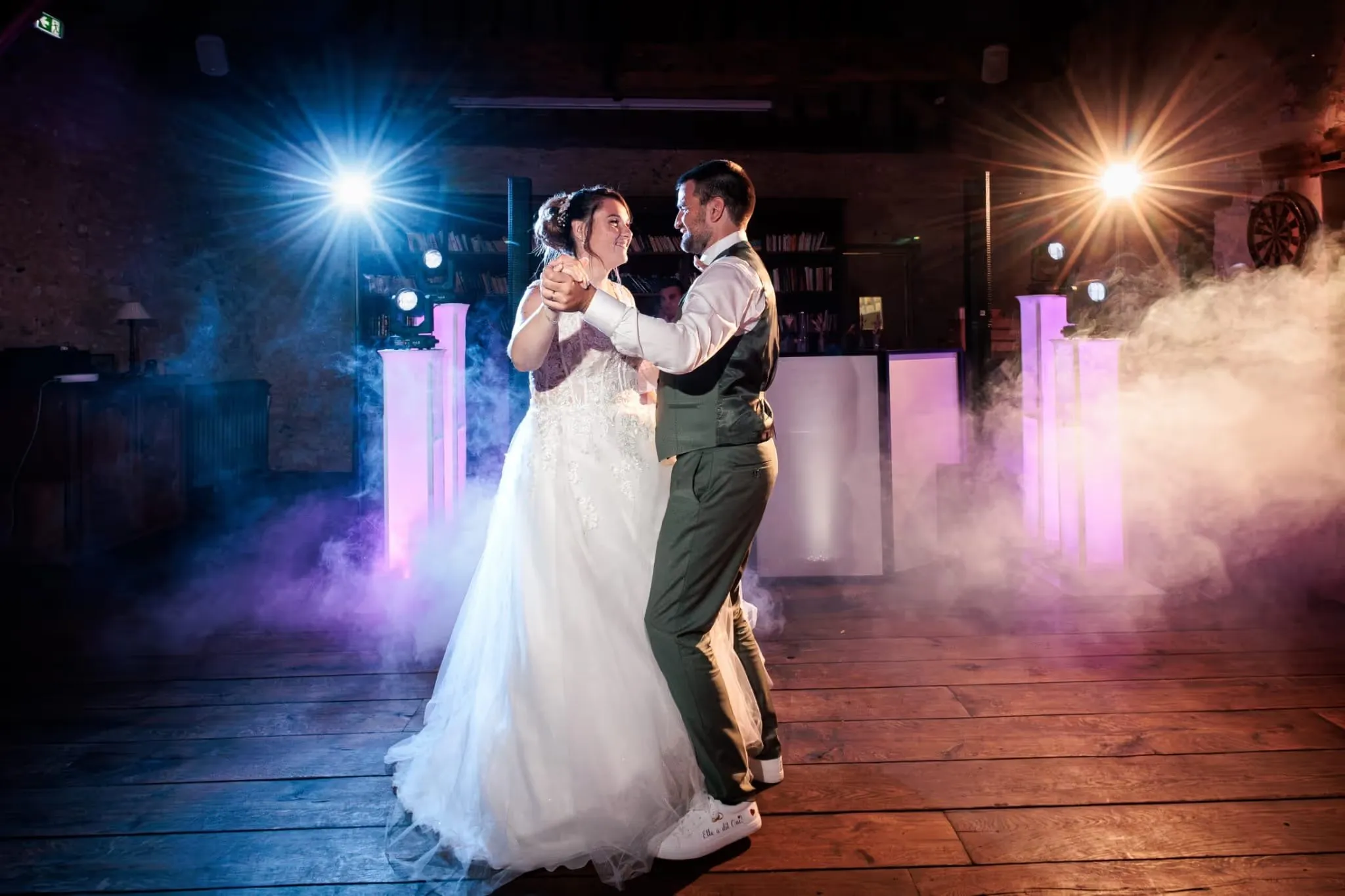 Première danse des mariés dans la fumée et les lumières de la piste